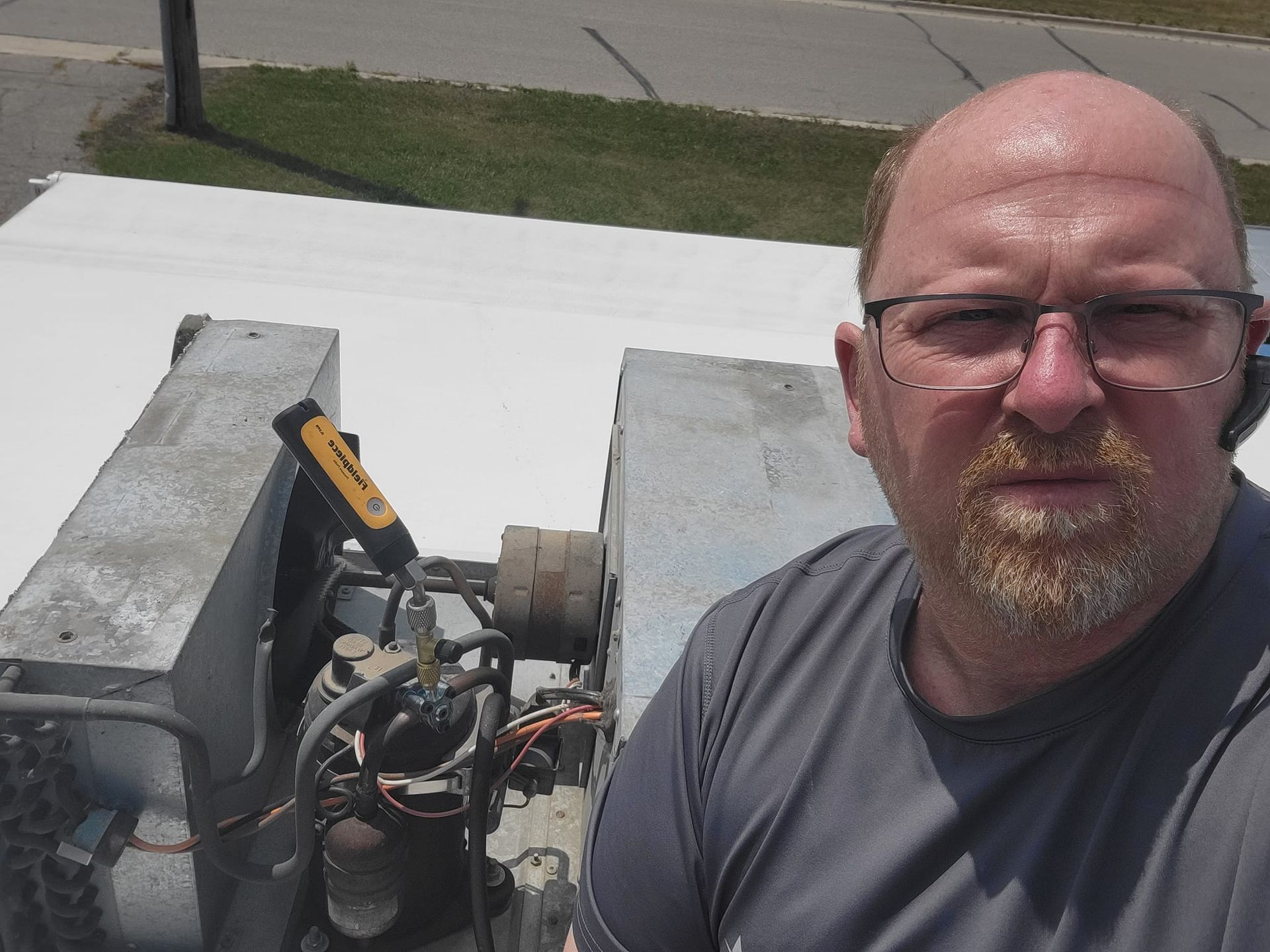 A man with glasses and a beard is standing in front of a machine