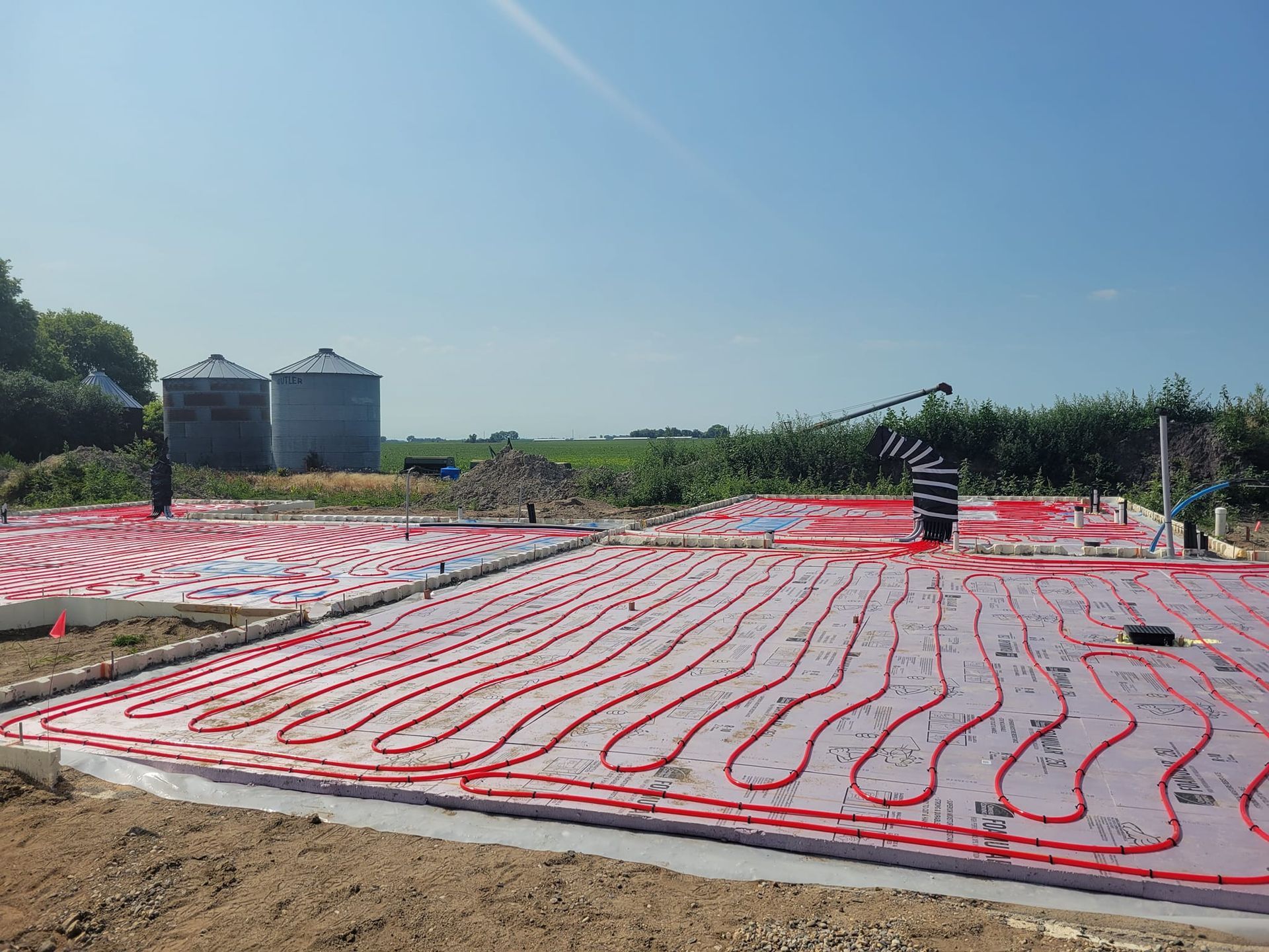 A construction site with a lot of red pipes on the ground.