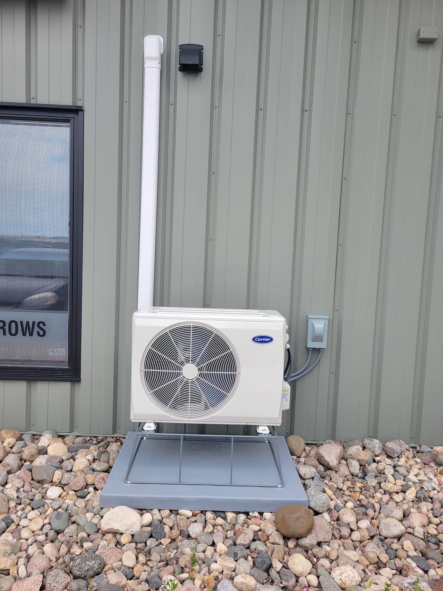 A white air conditioner is mounted on the side of a building.