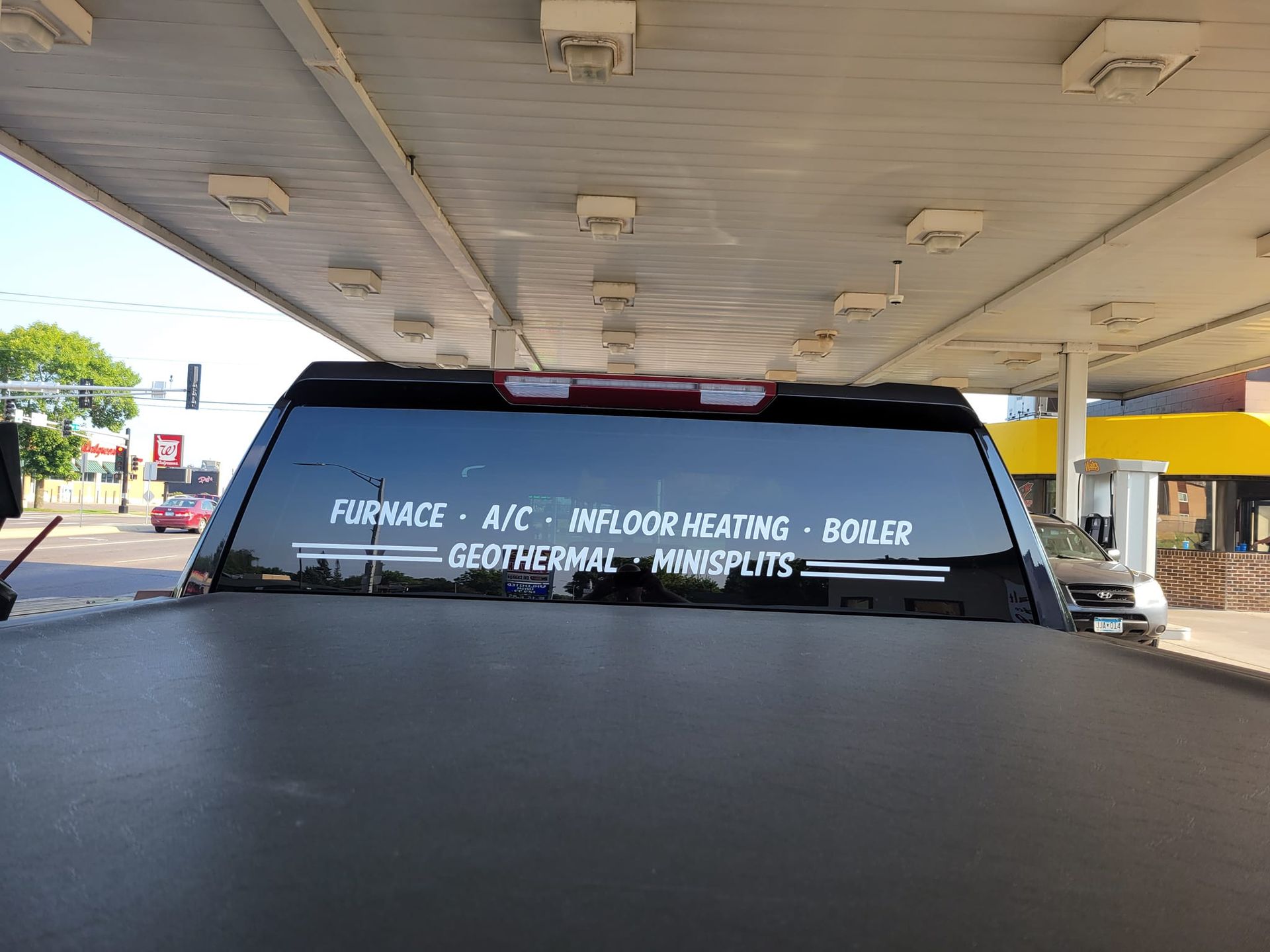 A truck is parked under a canopy at a gas station.