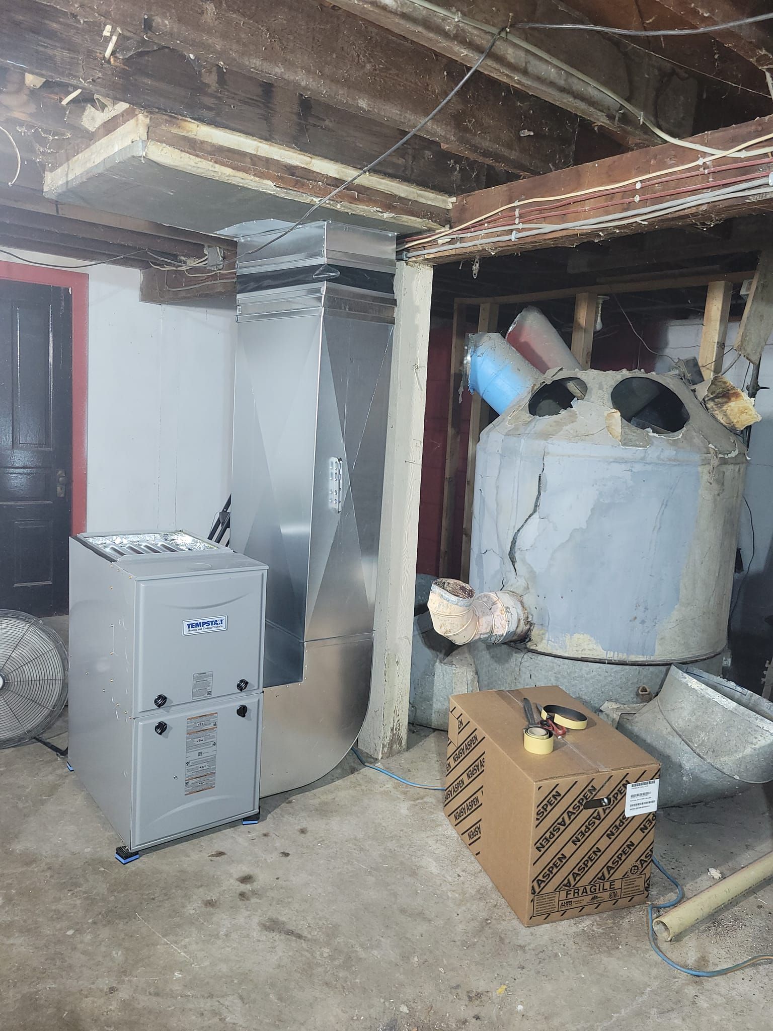 A basement with a furnace and a box on the floor.