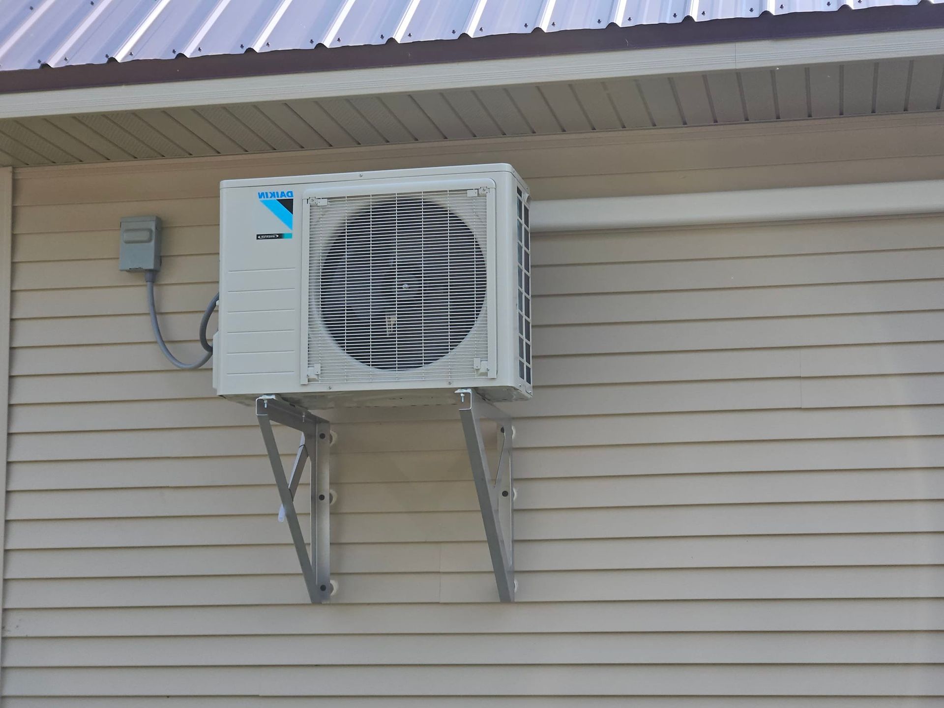 A white air conditioner is mounted on the side of a brick building.