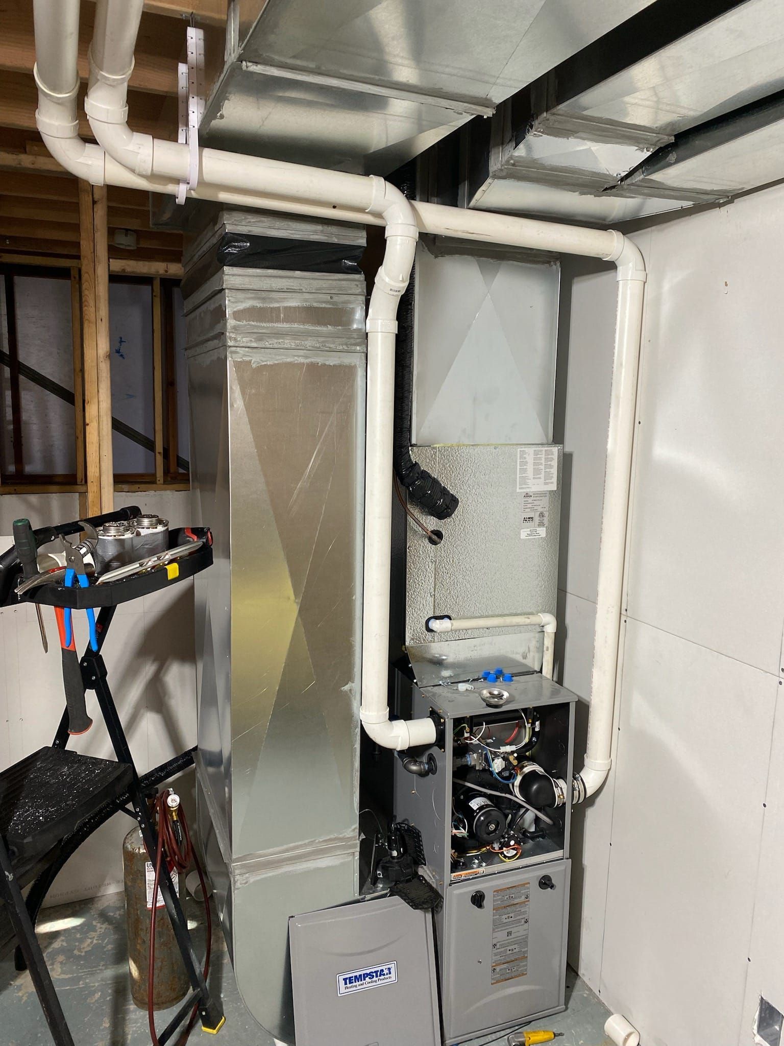 A basement with a furnace and pipes coming out of it.