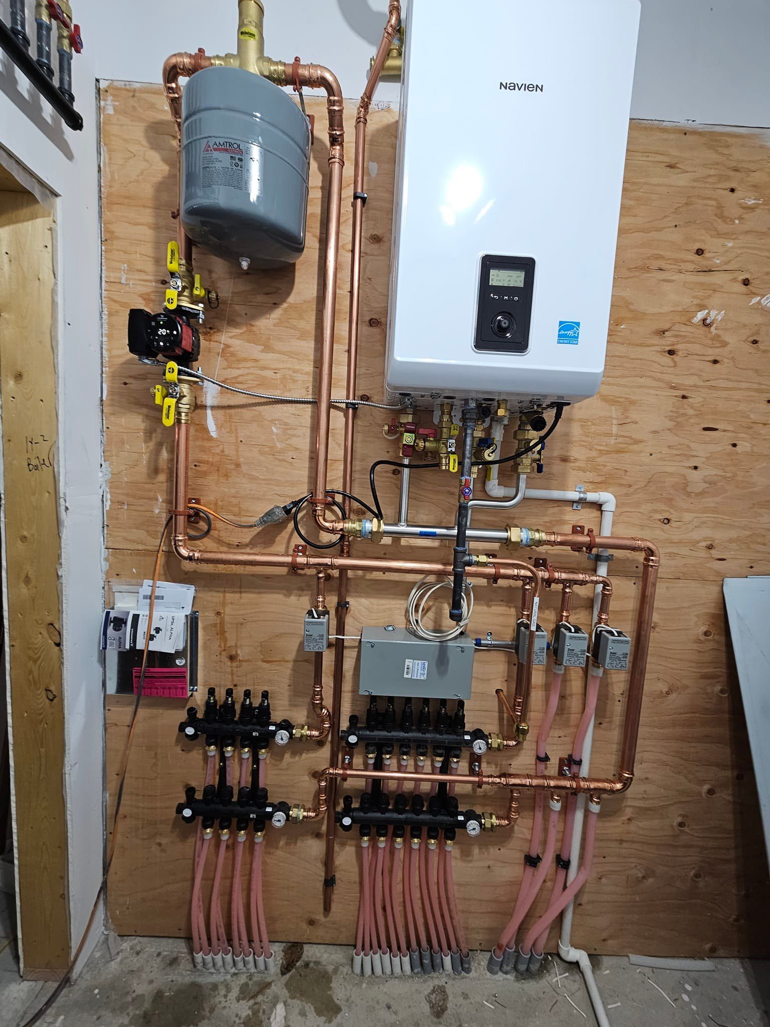 A room with a lot of pipes and a boiler on the wall.