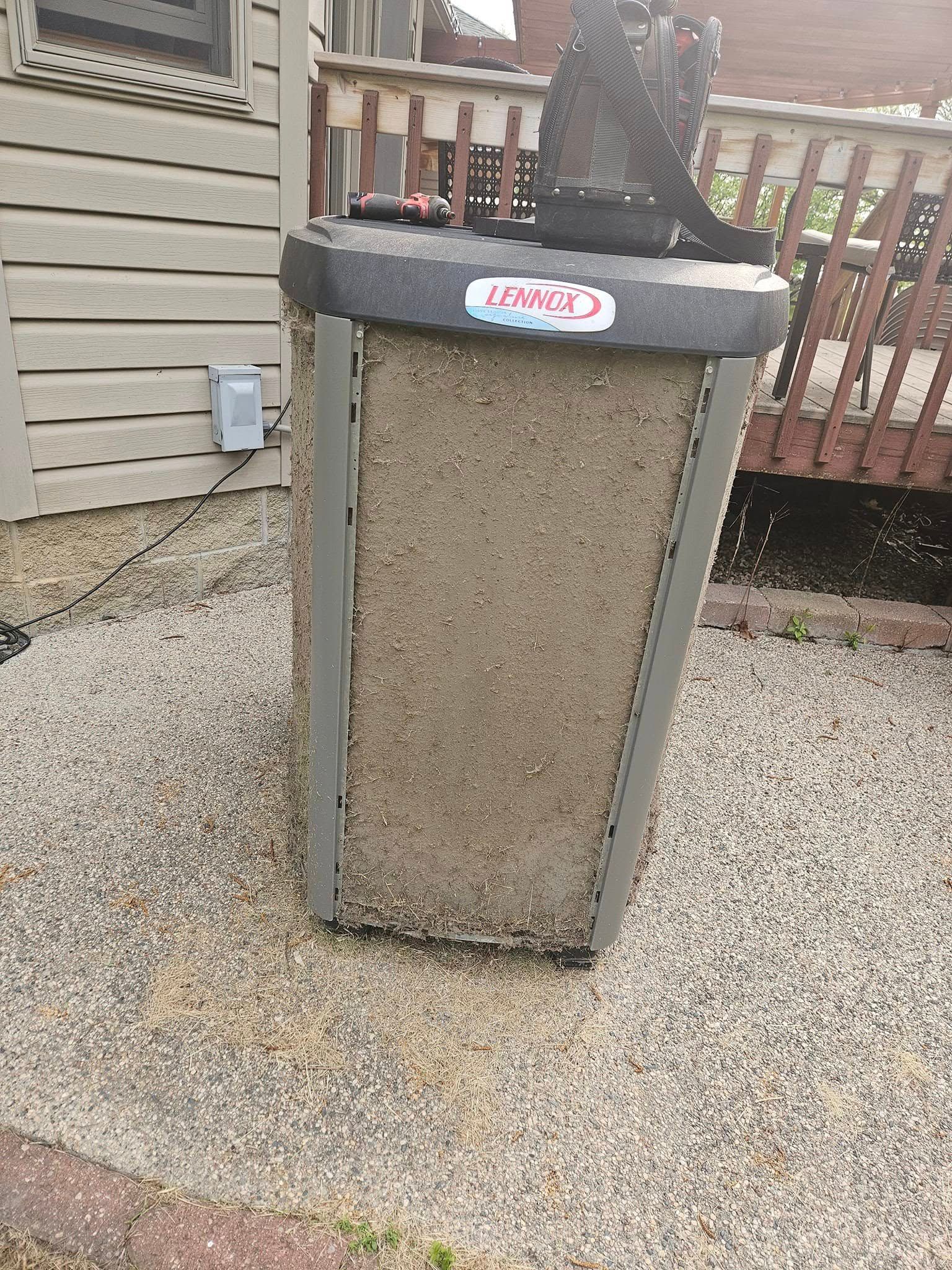 An air conditioner is sitting on the ground in front of a house.