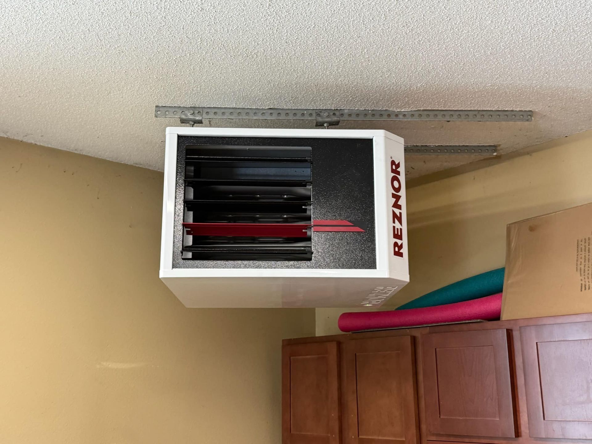A reznor heater is hanging from the ceiling in a garage.