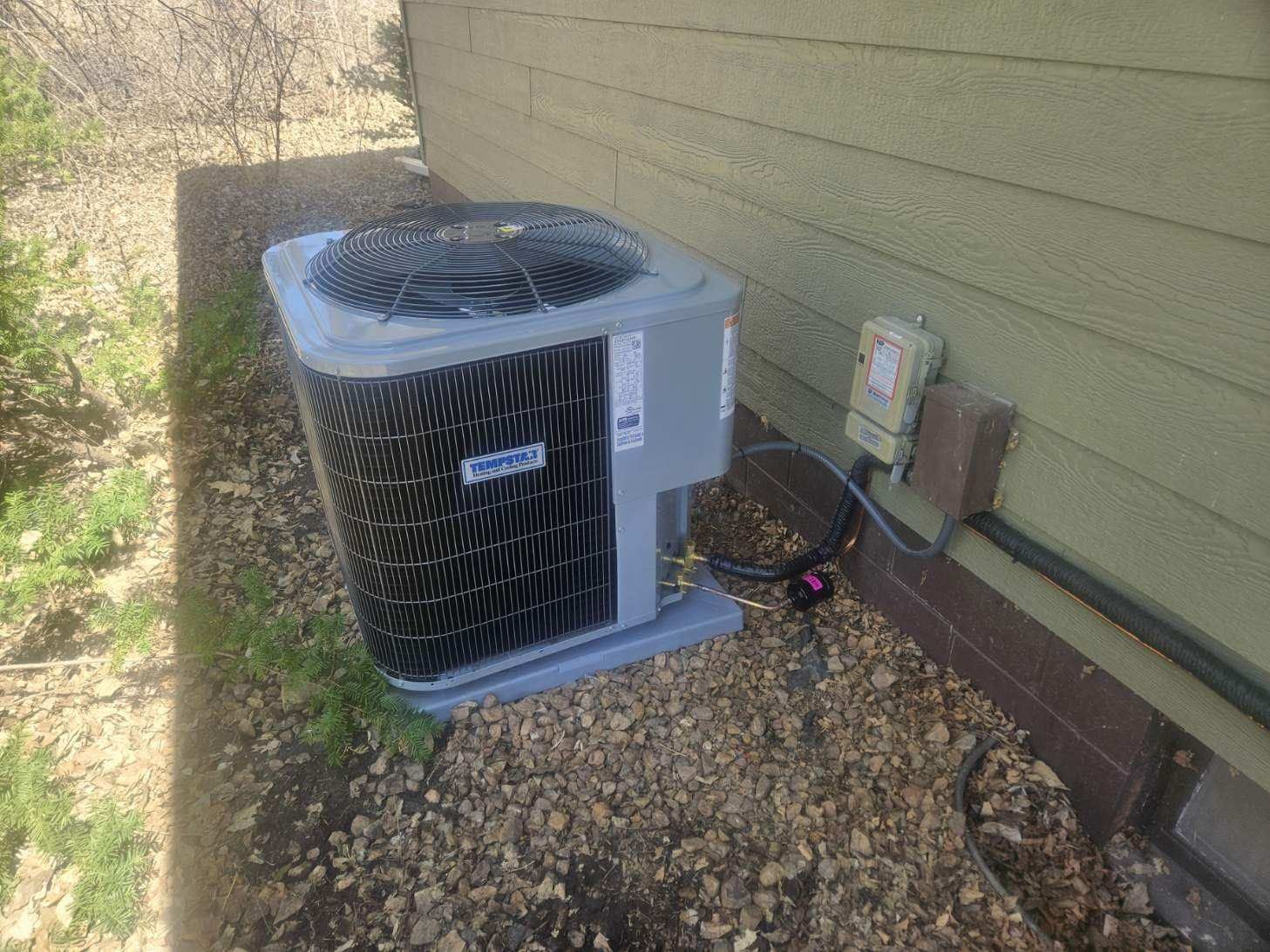 An air conditioner is sitting on the side of a house.