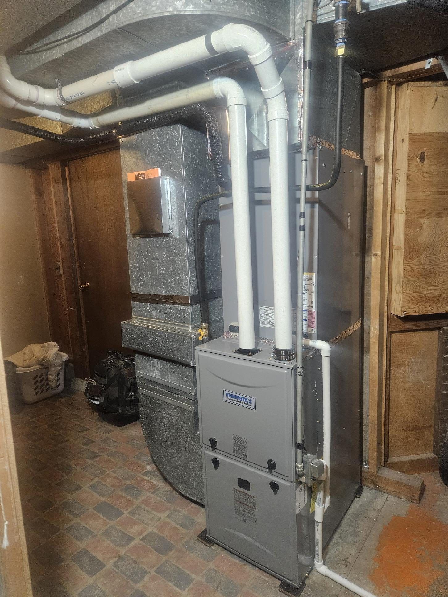 A basement with a furnace and pipes coming out of it.