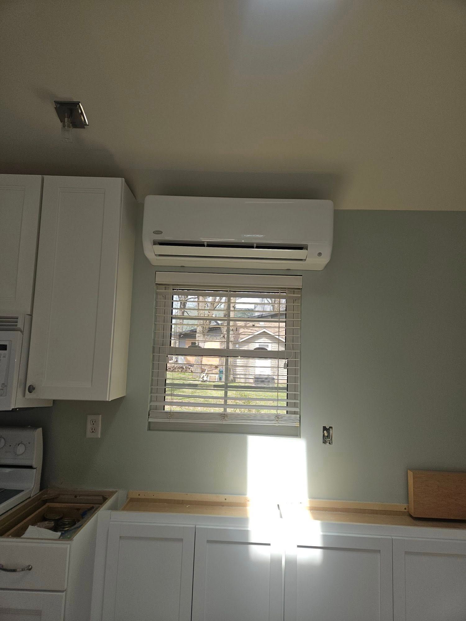 A kitchen with white cabinets and a window with blinds