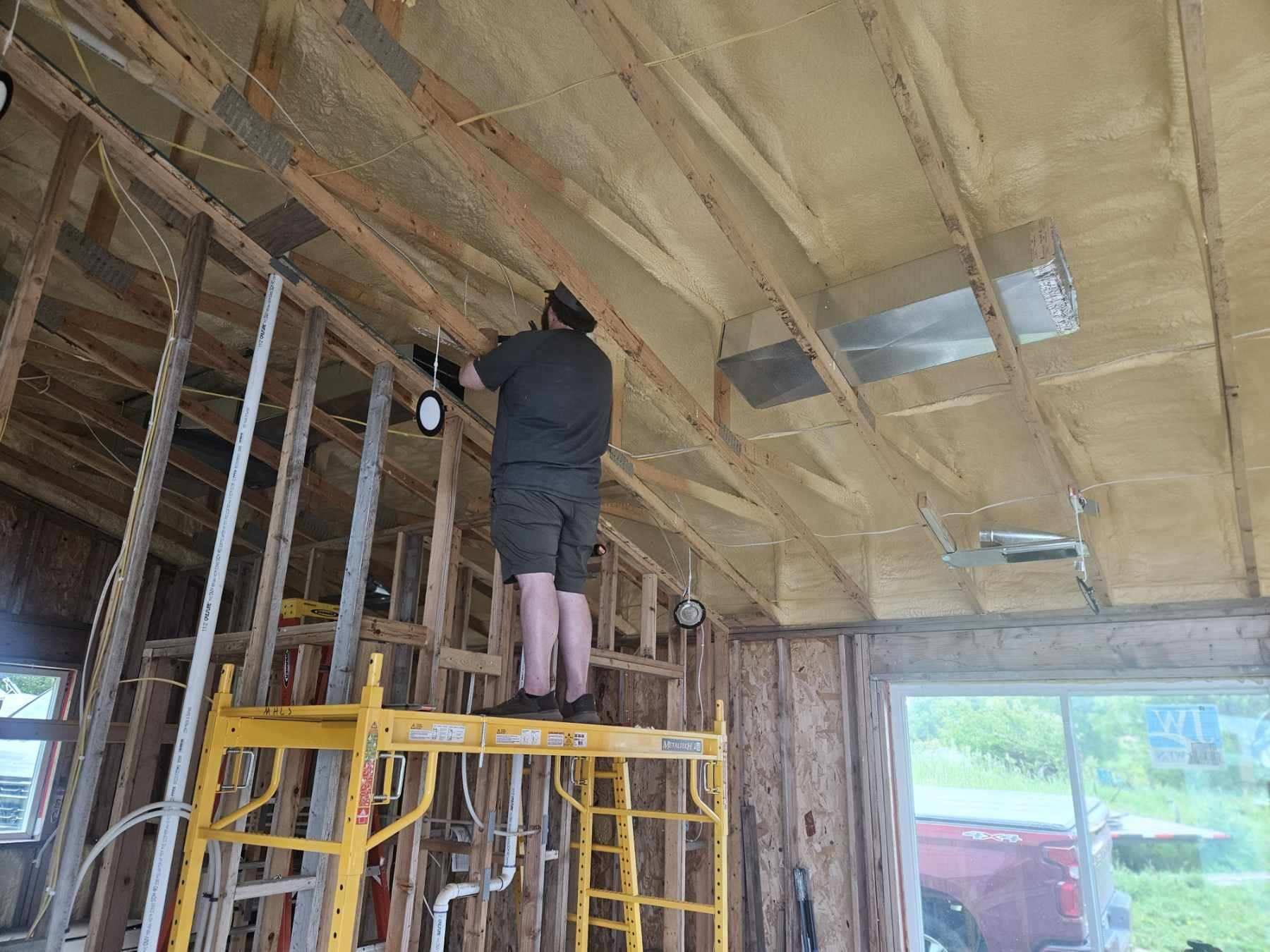 A man is working on the ceiling of a building.