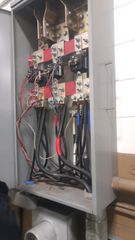 Open electrical cabinet with wiring, relays, and circuit components mounted inside.