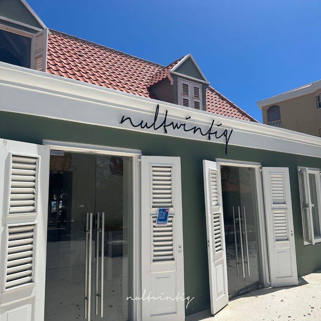 A green building with white shutters and a sign that says ' nullwinfig ' on it