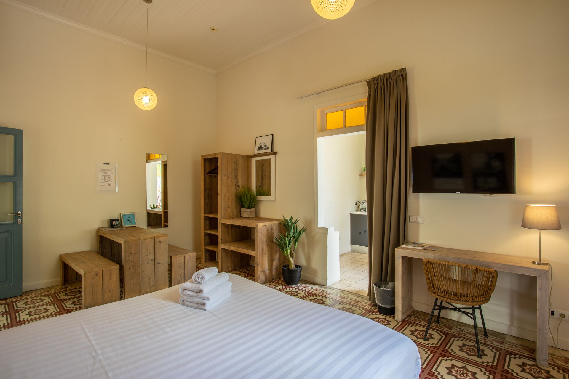 A hotel room with a king size bed , desk , chair and television. t Klooster Hotel Curacao