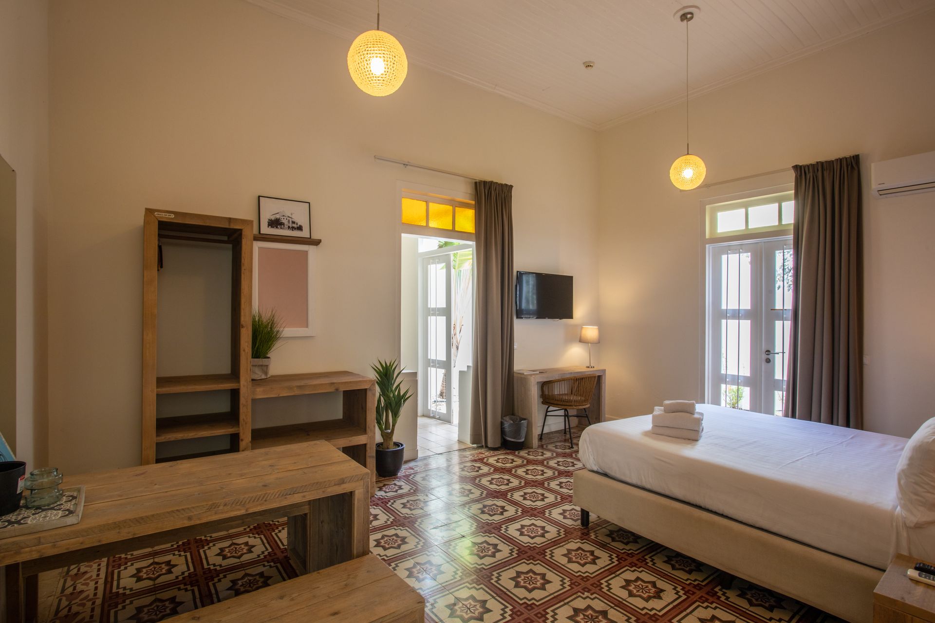 A hotel room with a king size bed , desk , and television. t Klooster Hotel Curacao