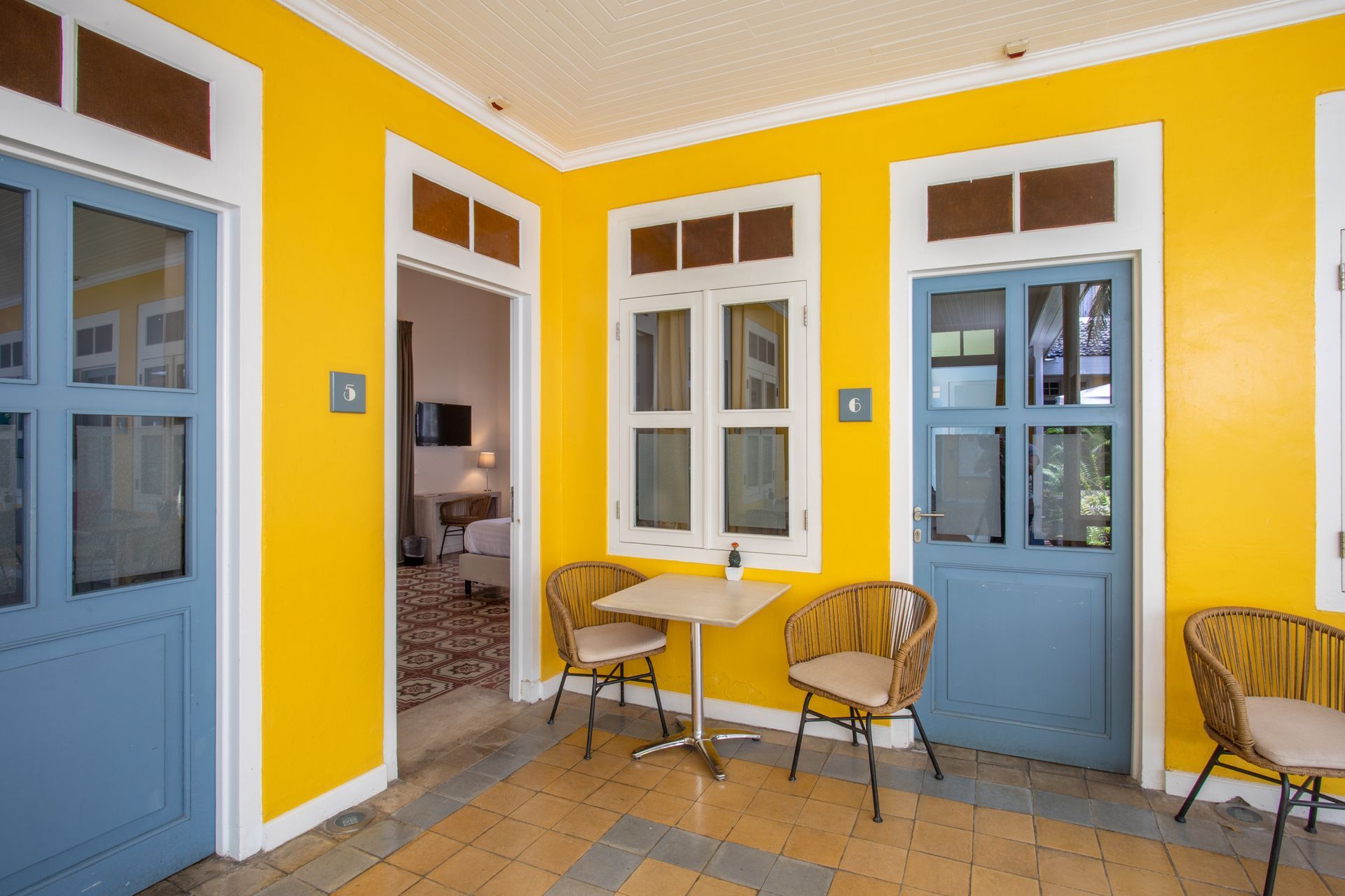 A room with yellow walls and blue doors has a table and chairs. t Klooster Hotel Curacao