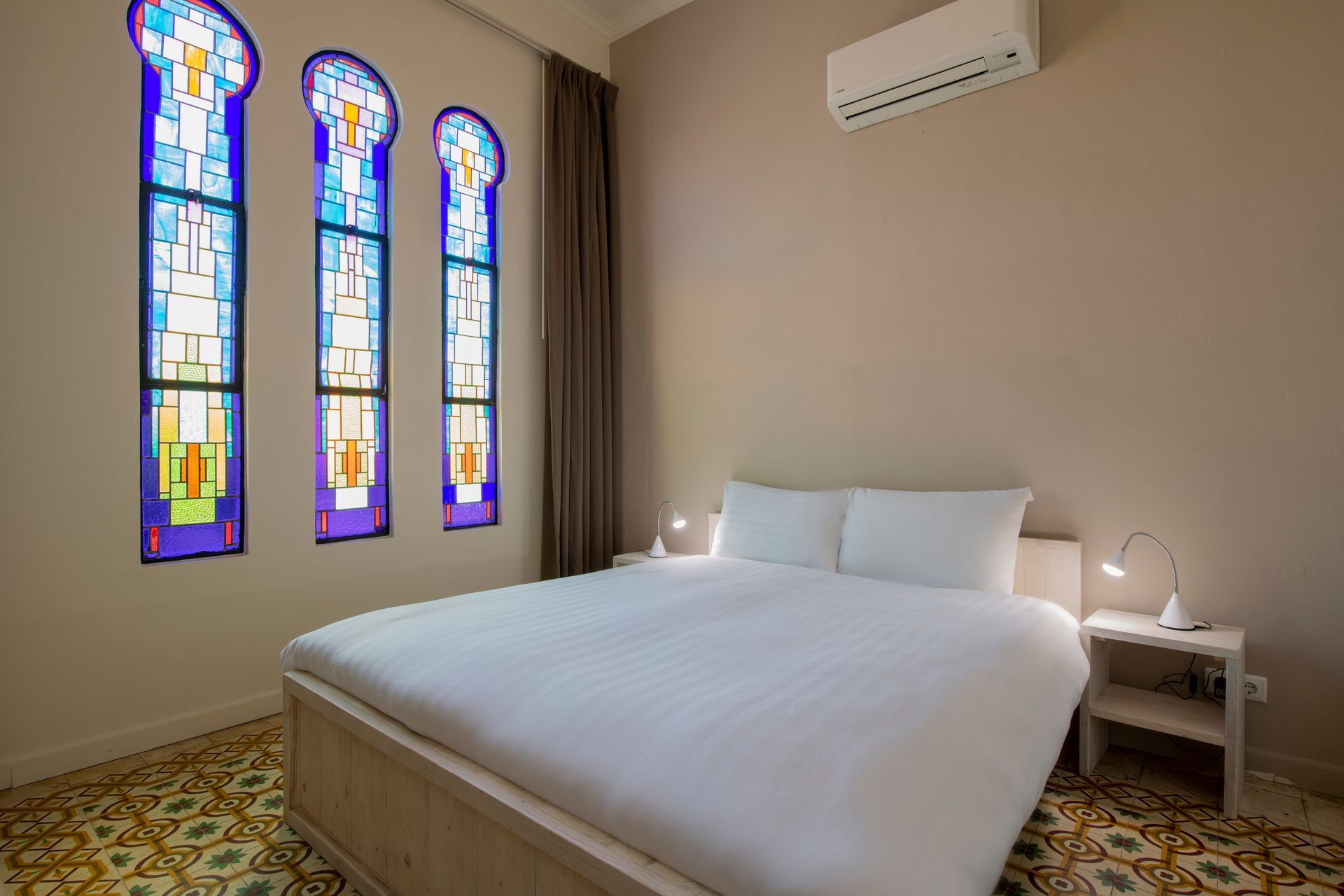 A bedroom with a bed and stained glass windows.