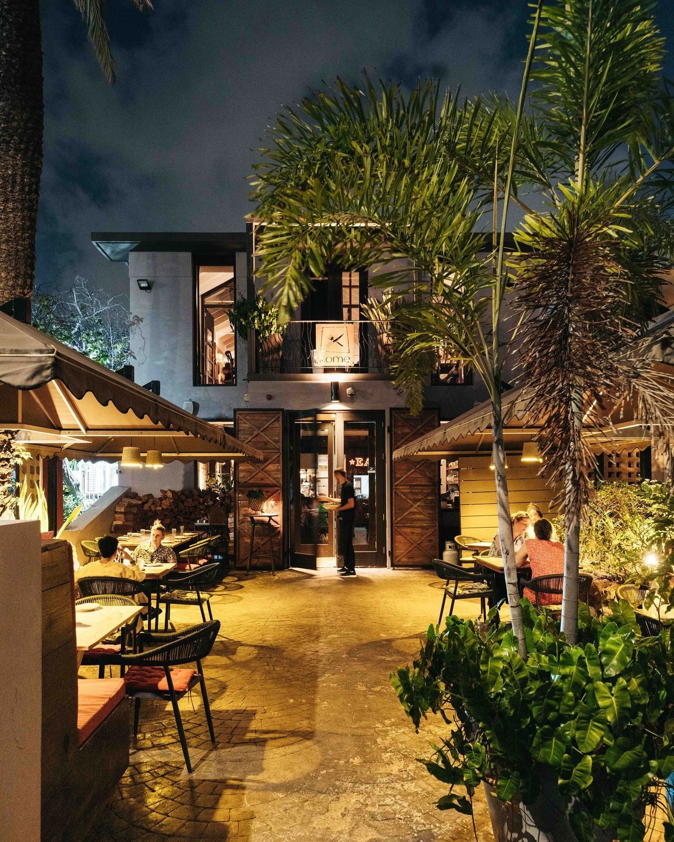 A restaurant with tables and chairs outside at night