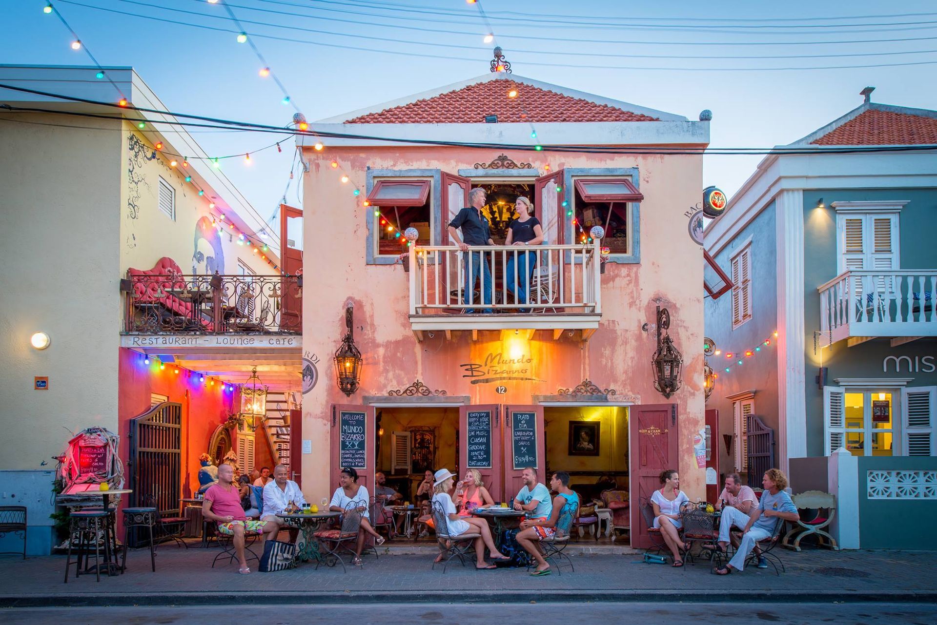 A group of people are sitting at tables outside of a building.