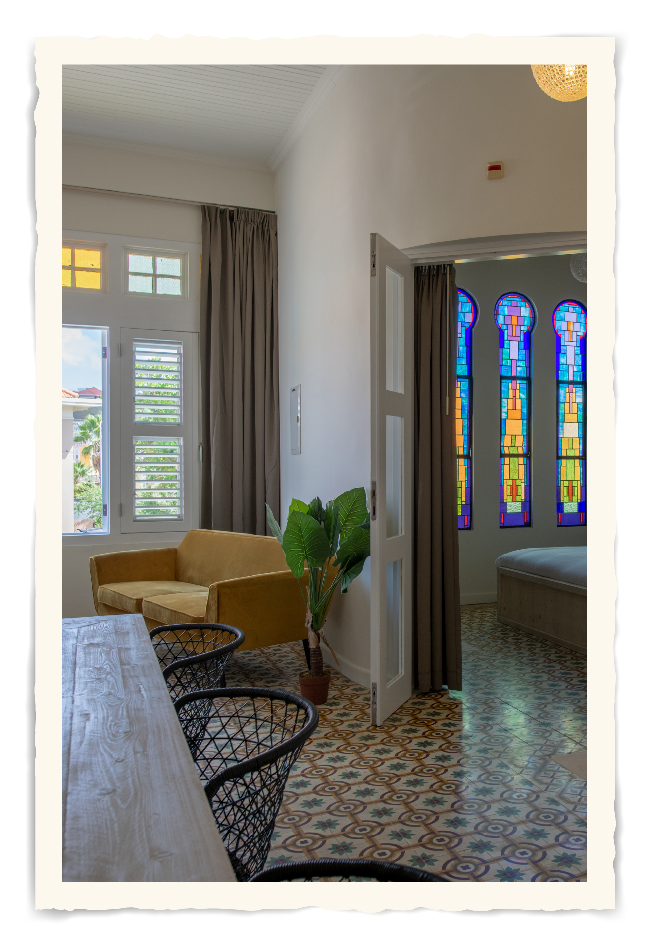 A living room with a couch , chair , table and stained glass windows.