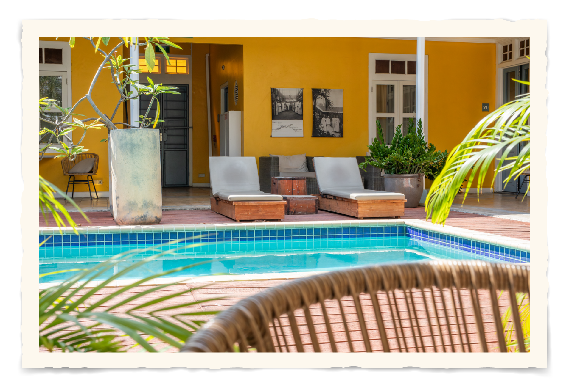 There is a swimming pool in front of a yellow house. t Klooster Hotel Curacao