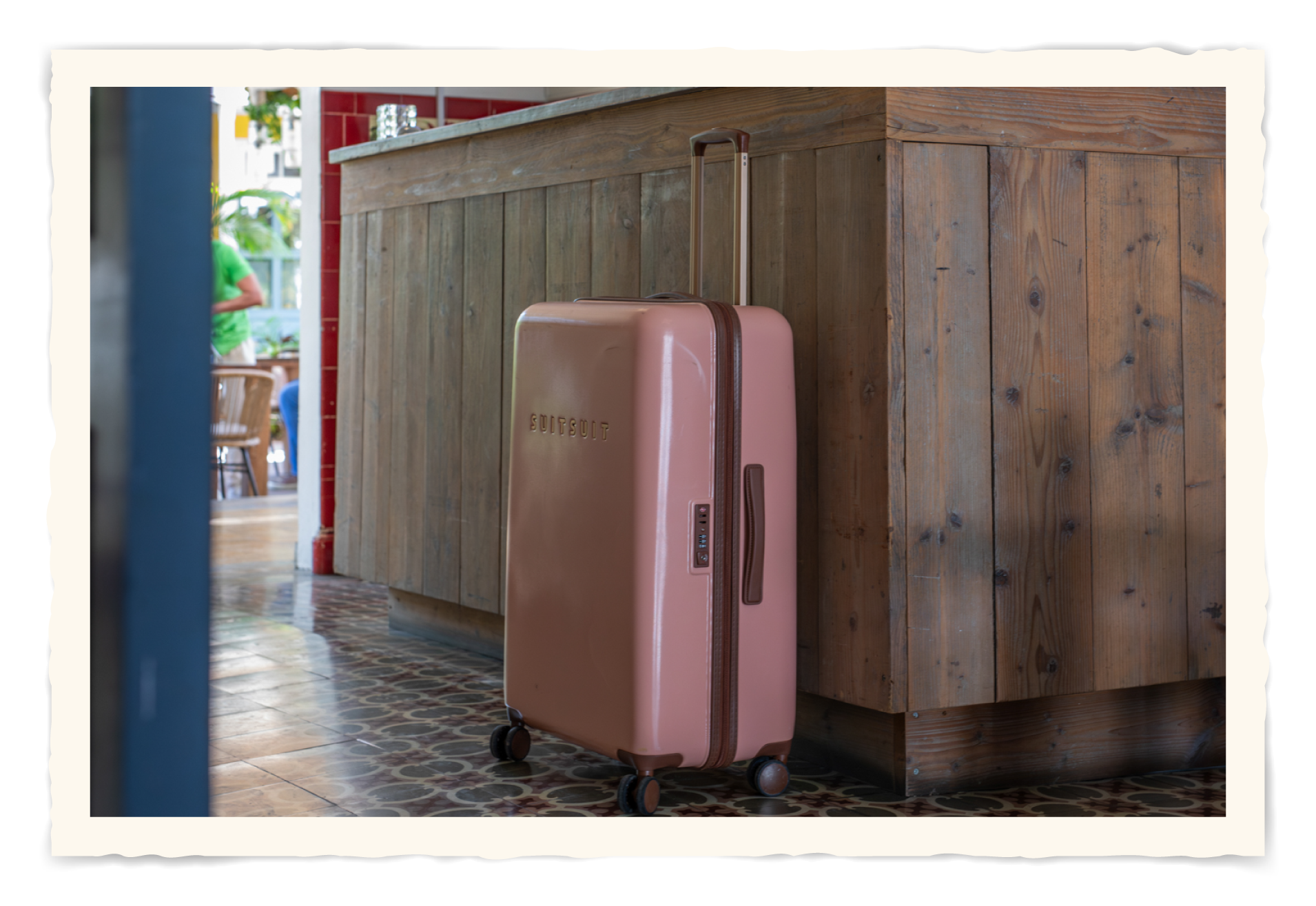 A pink suitcase is sitting on the floor next to a wooden counter. t Klooster Hotel Curacao