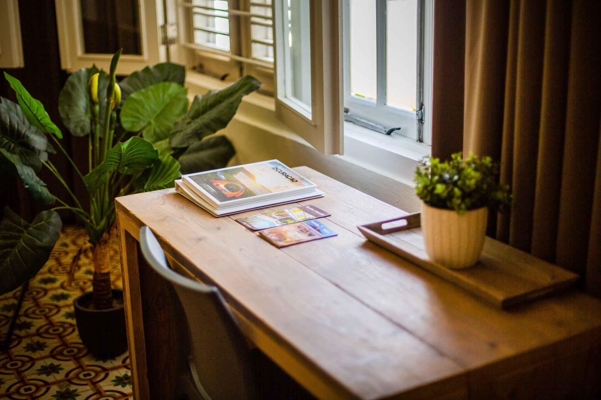 A wooden desk with a potted plant on it in front of a window. t Klooster Hotel Curacao