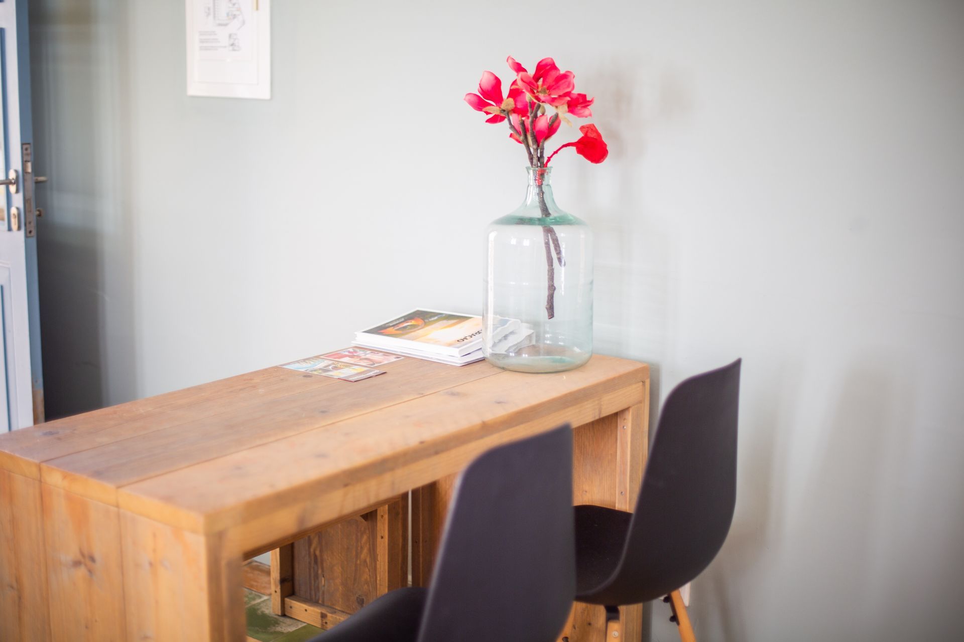 A wooden table with two chairs and a vase of flowers on it.