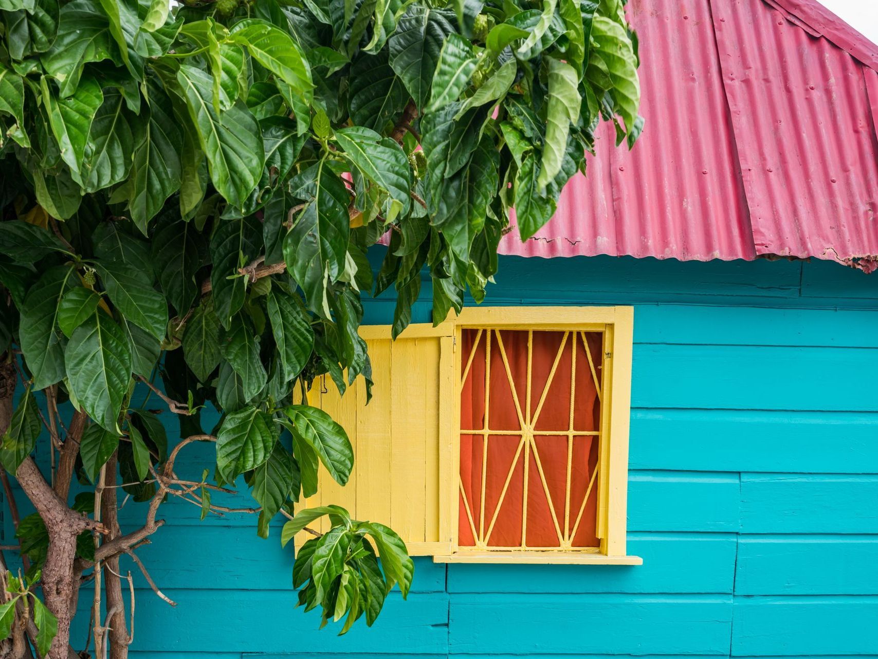 A blue house with a red roof and a yellow window.