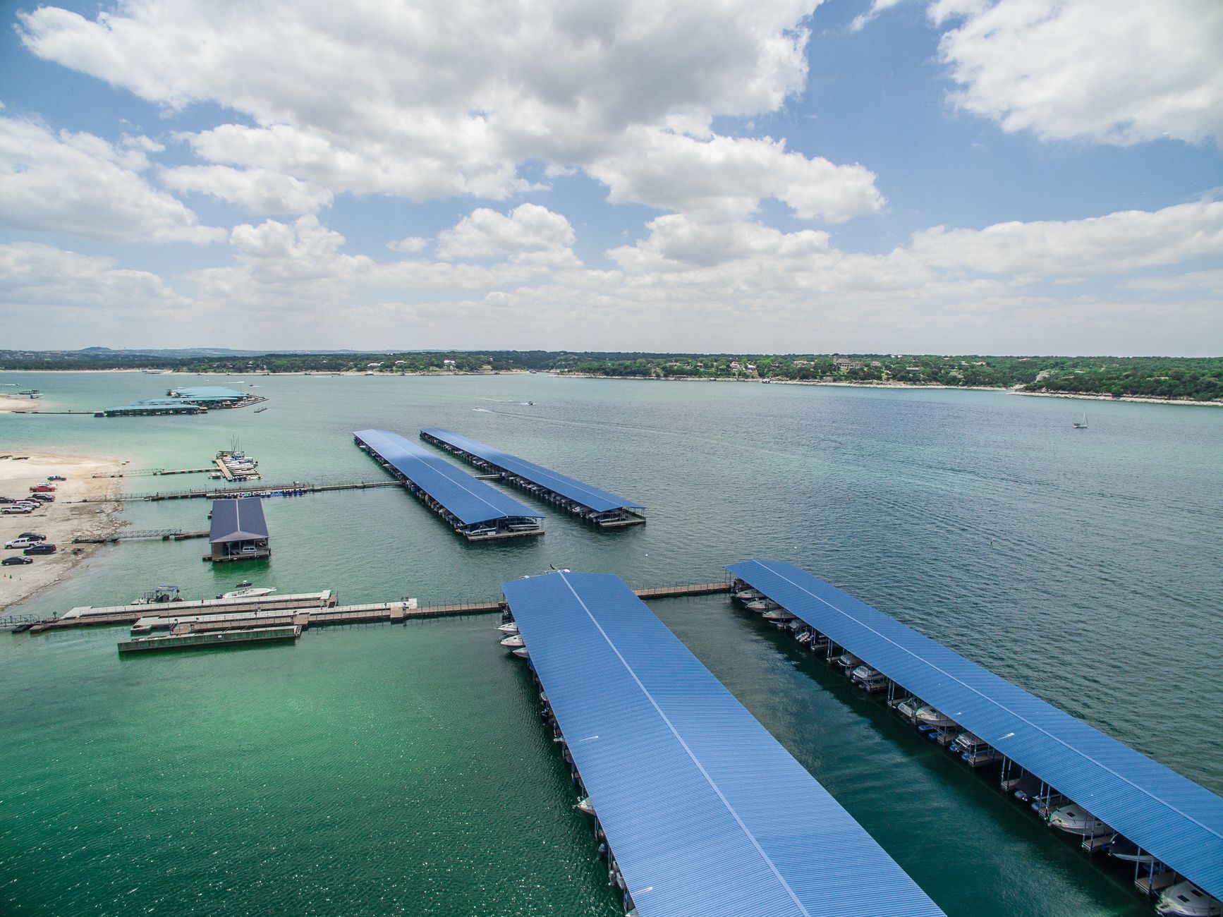 Aerial view of solar panel installations floating on turquoise water. Sunny day with clouds.