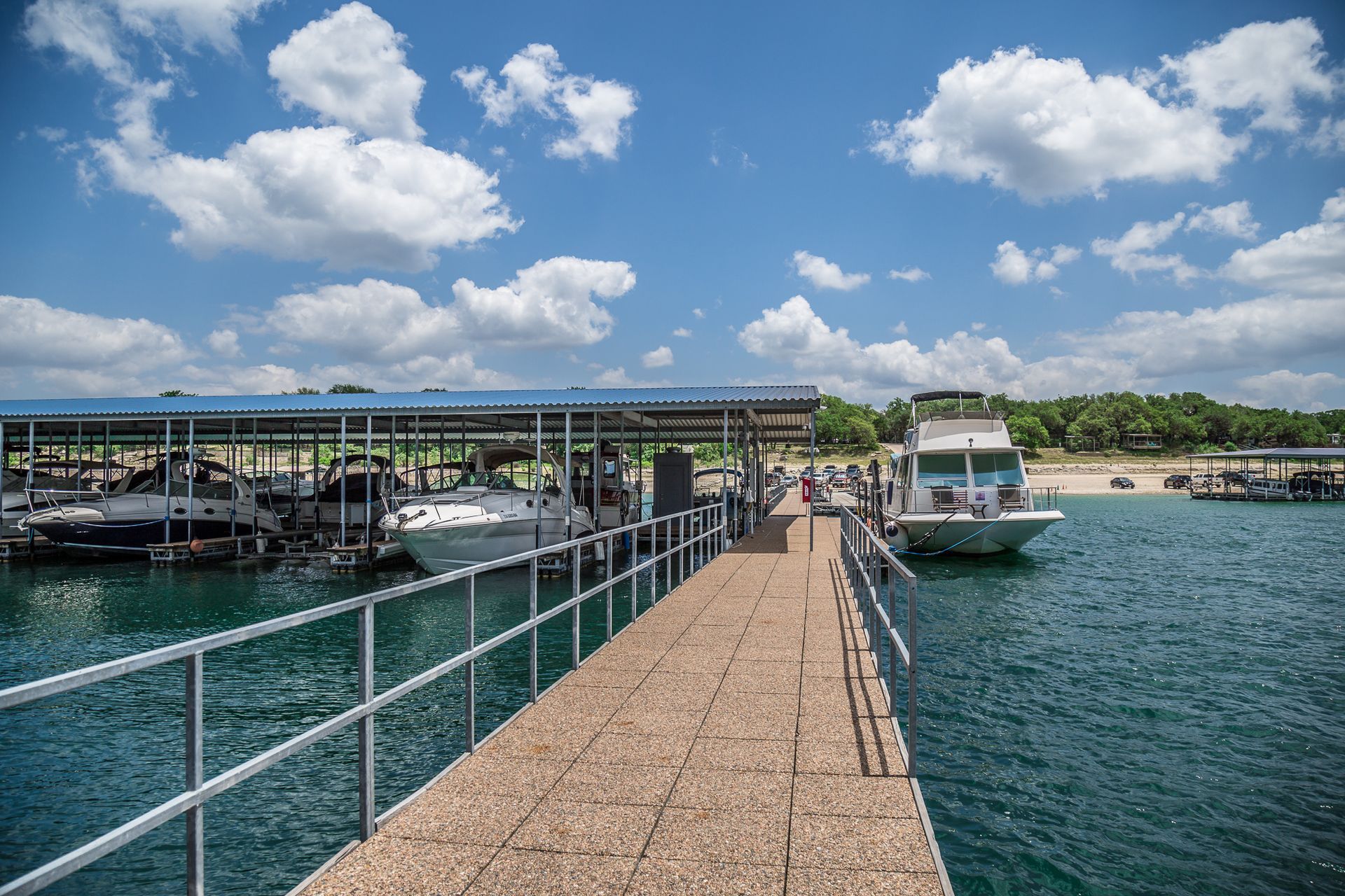 Dock with boats on a lake, sunny day with blue sky and clouds.