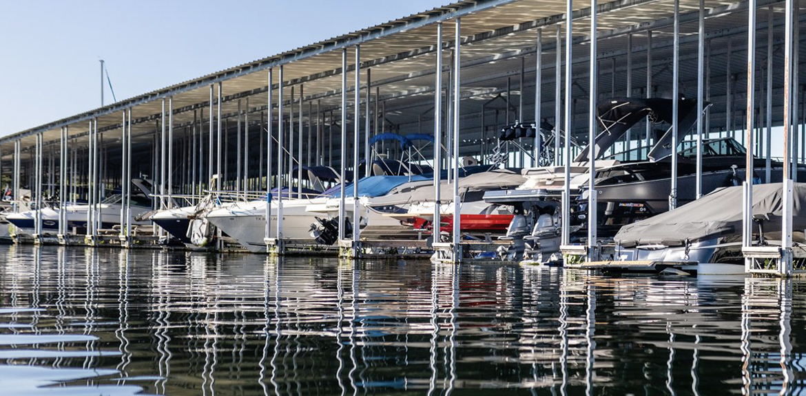 A young boy in a life jacket is looking out over a lake.