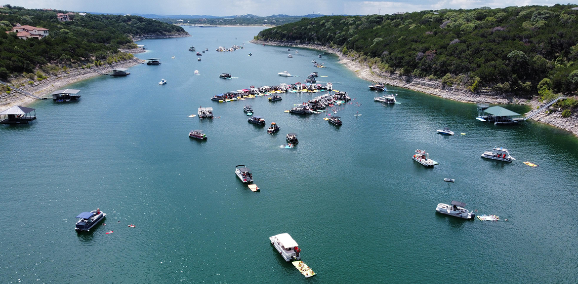 Boats on a lake surrounded by trees and shore.