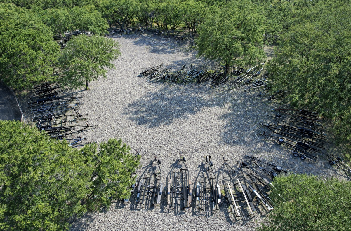 Overhead view of a circular clearing in a grove of trees; old tree trunks arranged around the edge of a stony area.