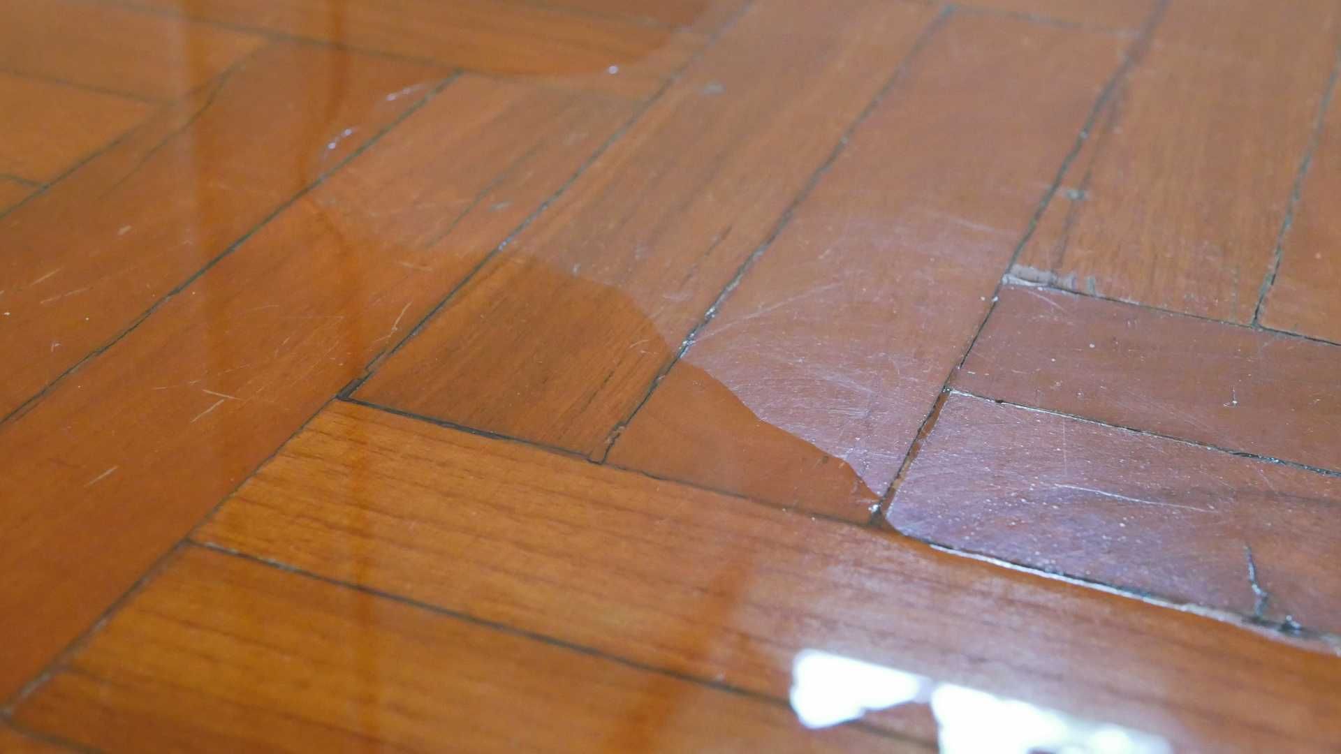 A close up of a wooden floor with water on it.