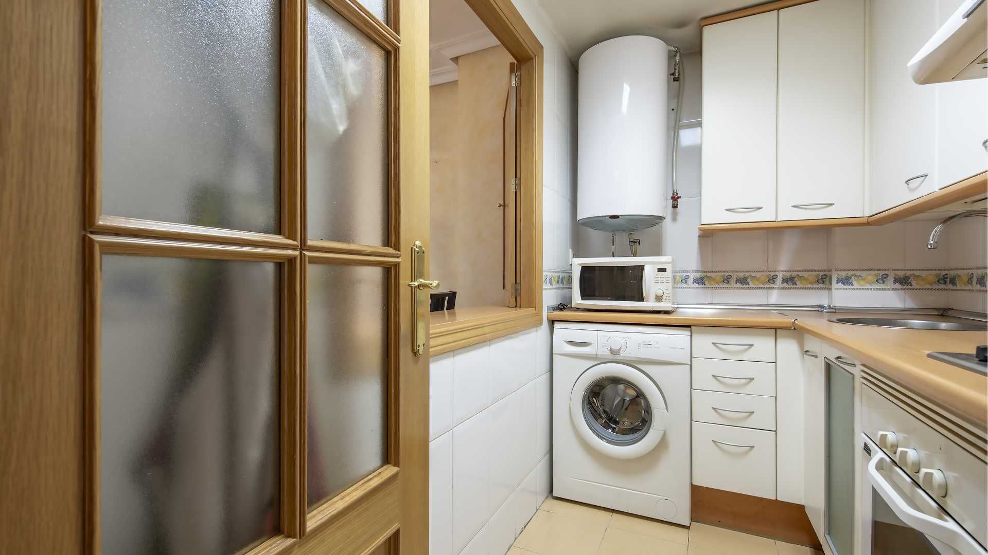 A kitchen with a washer and dryer and a microwave.