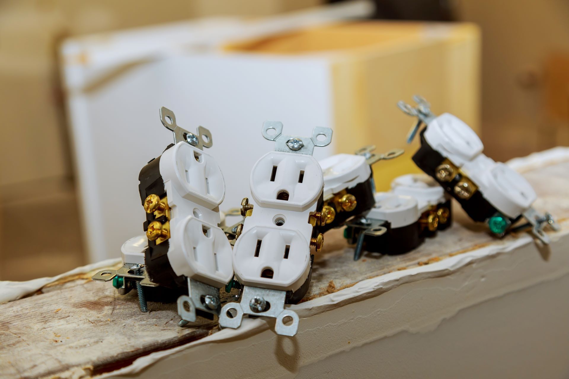 Several white electrical outlets with copper and green details sit on a wooden surface.