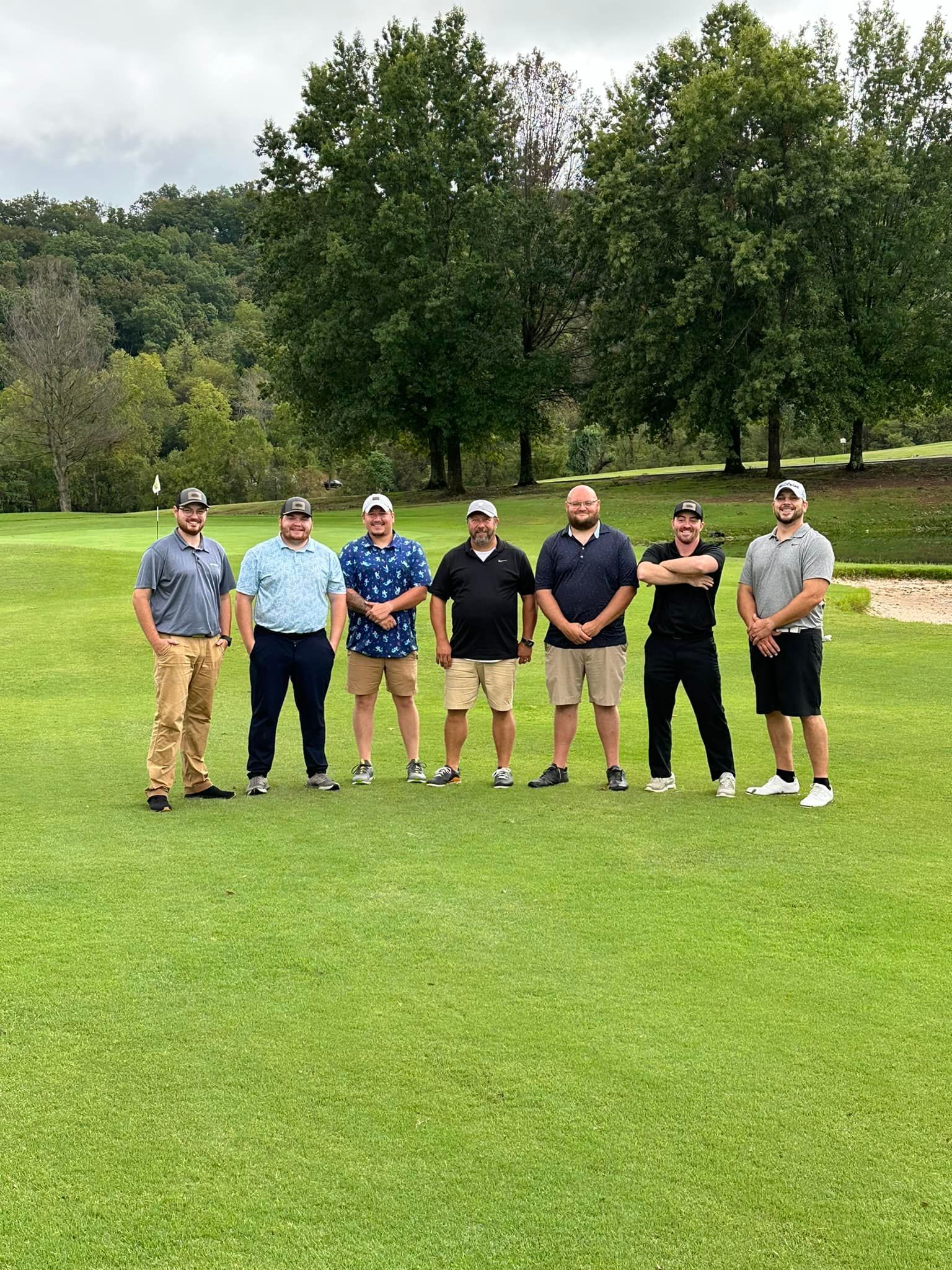 A group of men are posing for a picture on a golf course.