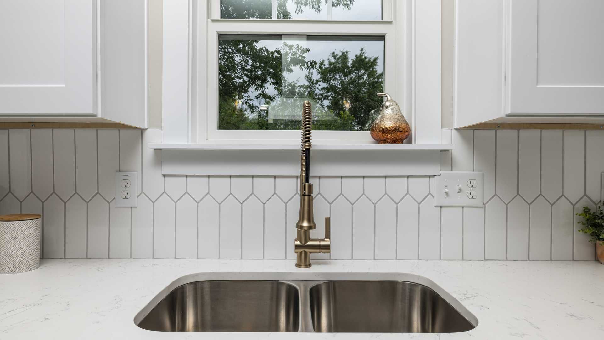 A kitchen sink with a faucet and a window in the background.