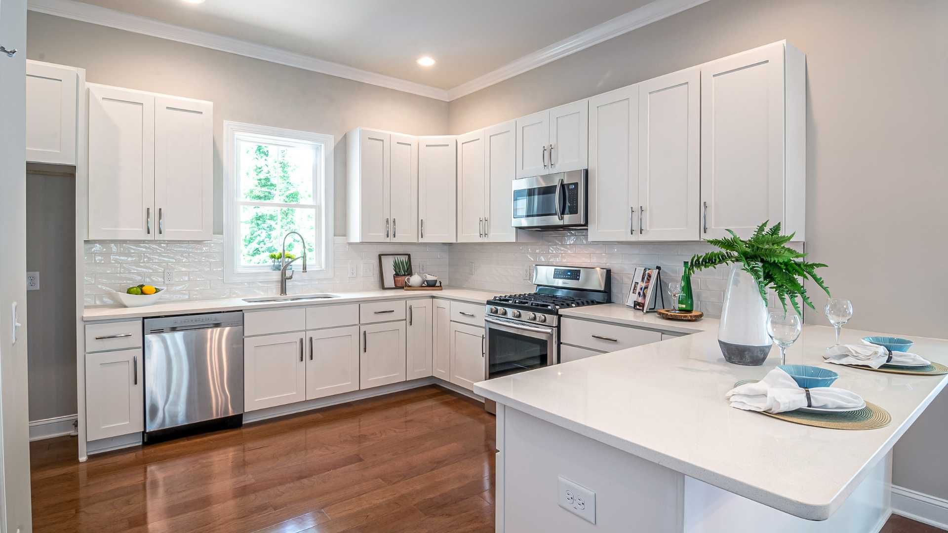A kitchen with white cabinets , stainless steel appliances , and hardwood floors.