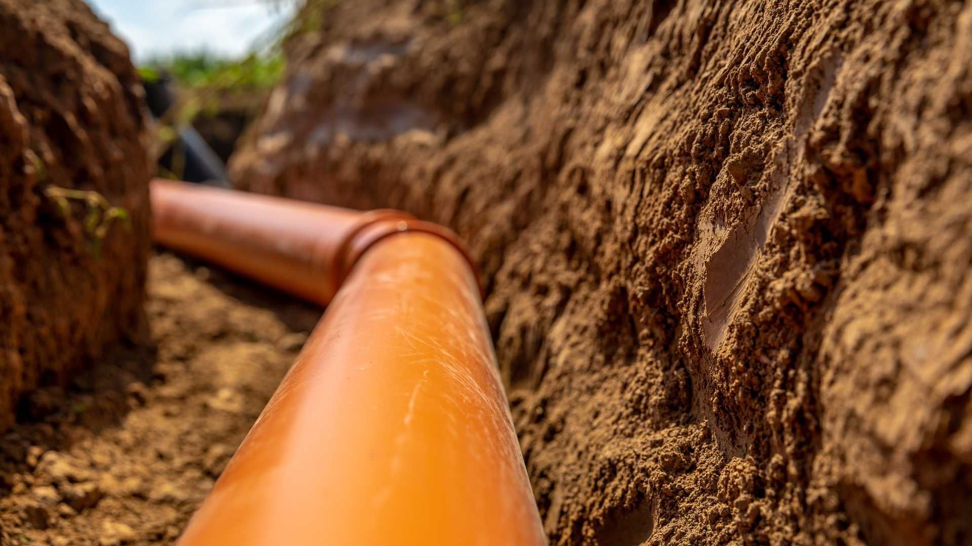 A pipe is being installed in a trench in the dirt.