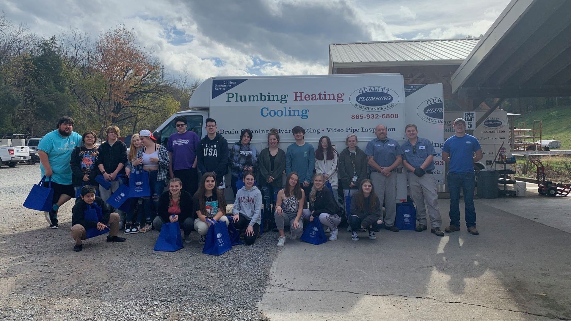 A group of people are posing for a picture in front of a plumbing company truck.