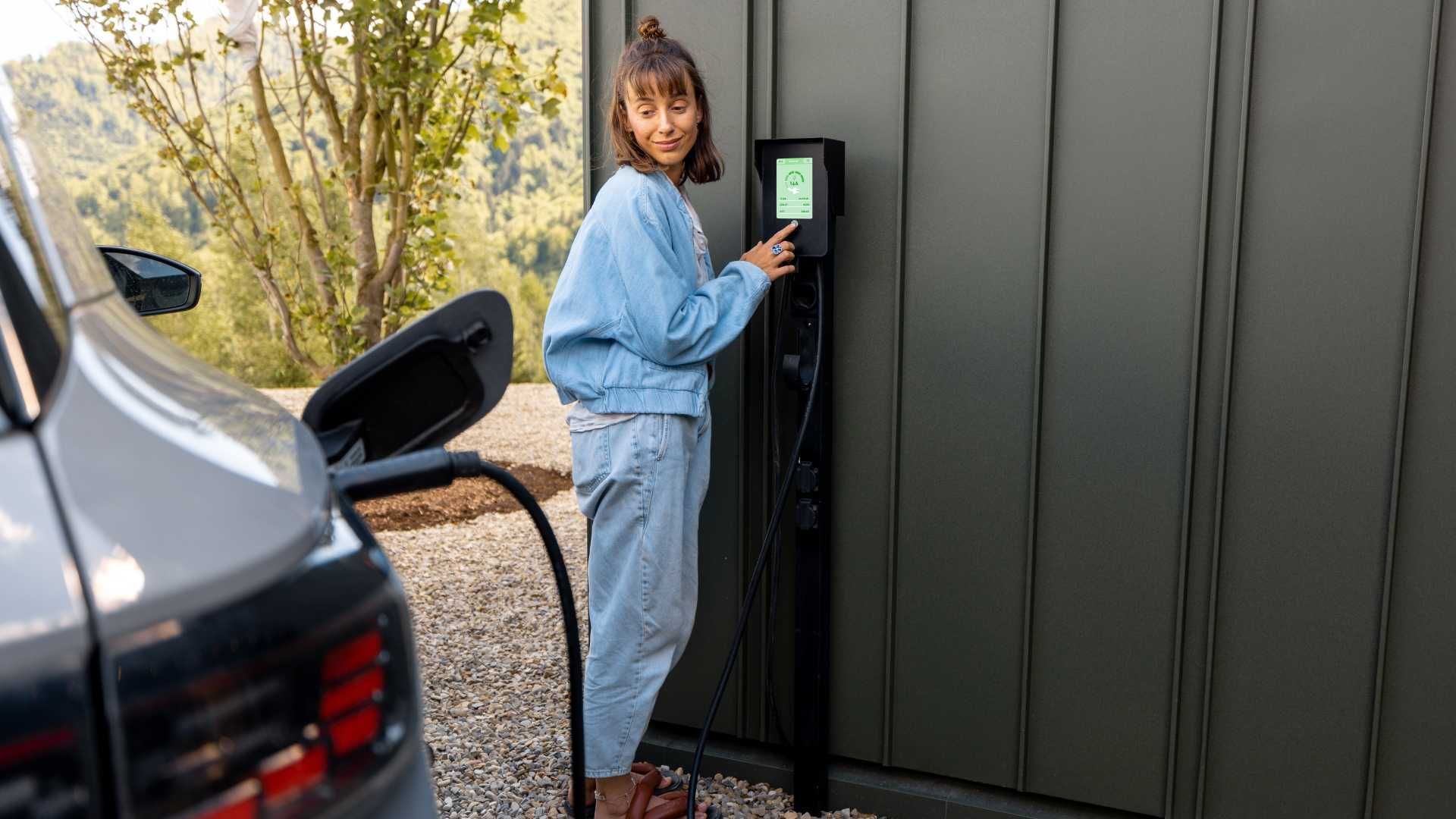 A woman is charging her electric car at a charging station.