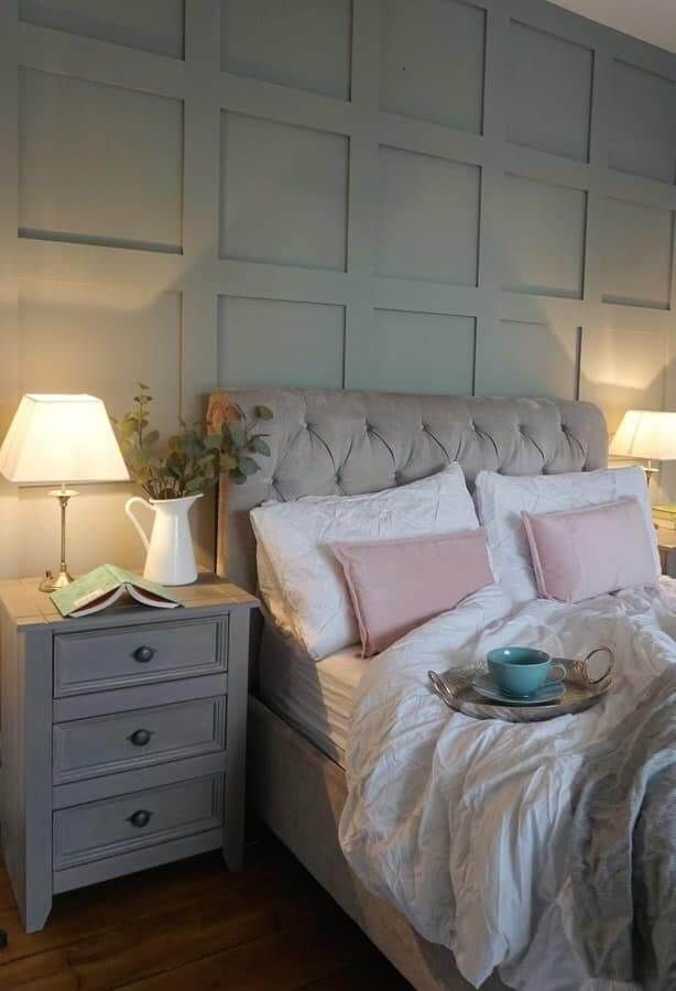 Bedroom with upholstered headboard, pale green paneled wall, two bedside lamps, and gray nightstand.