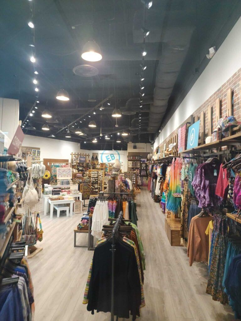 Inside a brightly lit boutique; merchandise on racks and shelves lines both sides.