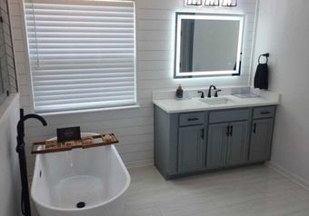 Bathroom with bathtub, vanity, and shiplap wall. Gray and white color scheme.