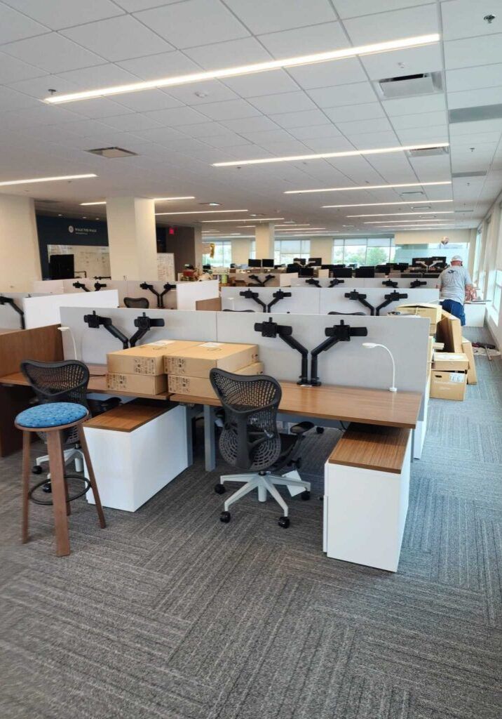 An office space with desks and cubicles, some employees present, neutral colors.