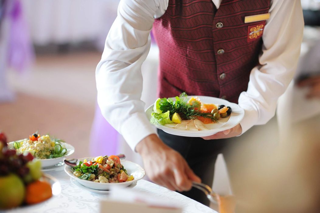 a waiter is holding a plate of food on a table