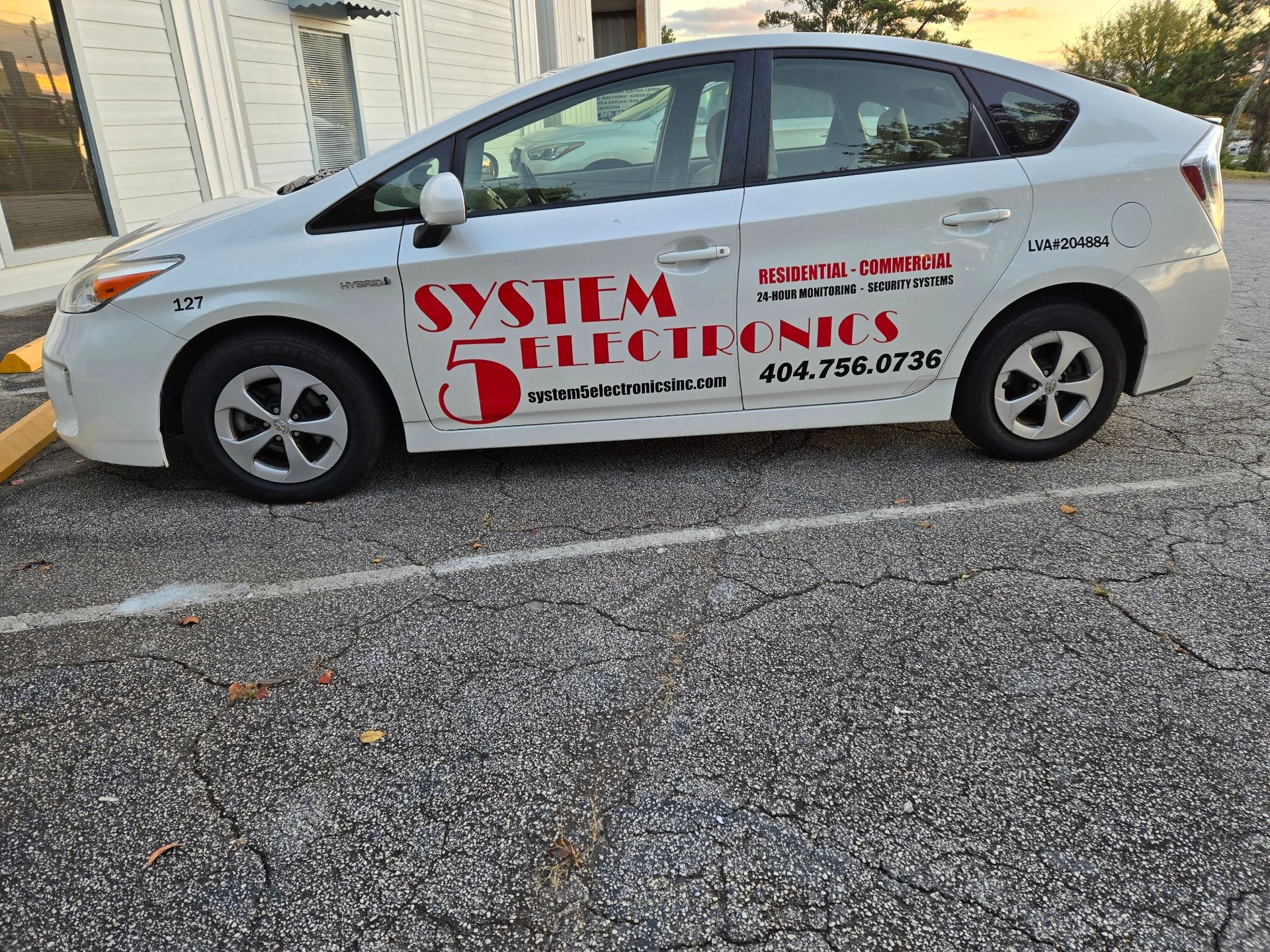 A white prius is parked in a parking lot.