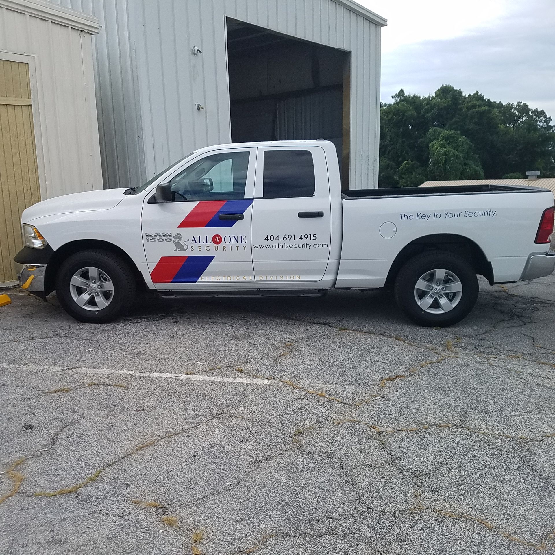 A white truck with blue and red stripes on the side is parked in front of a building.