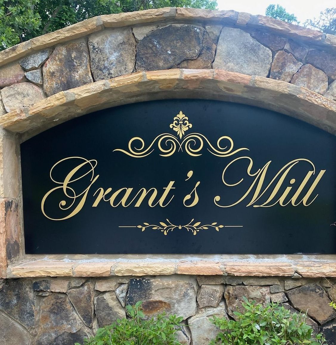 A black and gold sign for grant 's mill